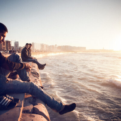 Men sitting on a wall looking at the ocean in Casablanca, Morocco.