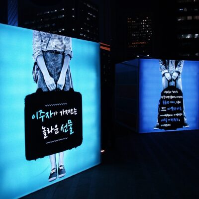 A display at an International Migrants Day campaign celebration in IOM Seoul depicting two people carrying luggage.
