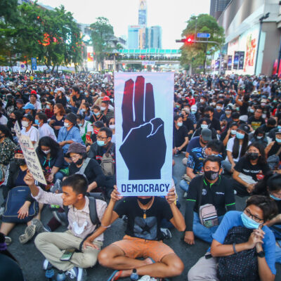 Pro-democracy demonstrators with banners sit on a road in Bangkok, October 2020.